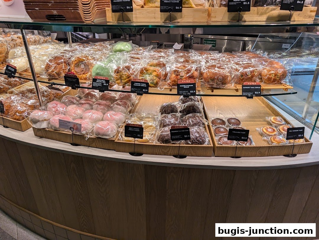 A display of freshly baked breads and pastries in plastic packaging at a bakery.