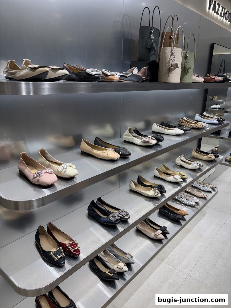 A display of various women's flat shoes and handbags on shelves in a retail store.