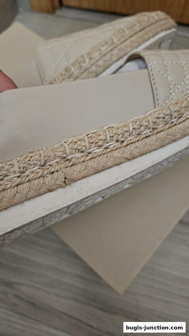 Close-up of beige espadrille sandals with quilted detailing and jute trim.