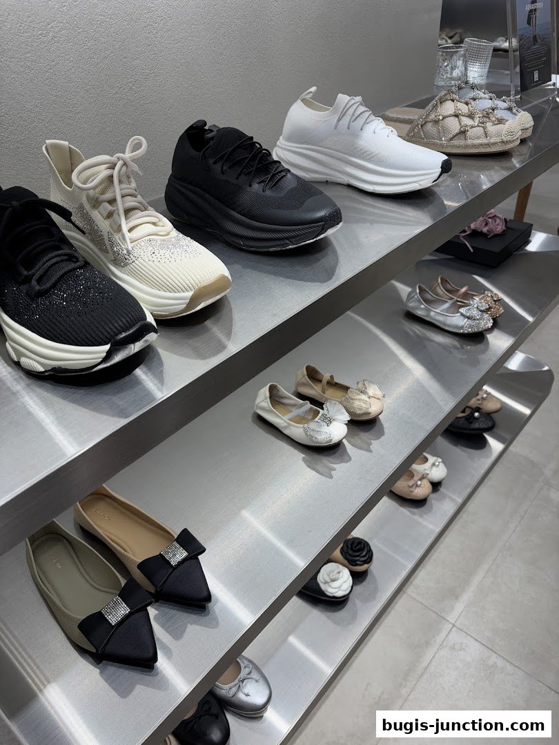 A display of various women's shoes, including sneakers and flats, on metal shelves.