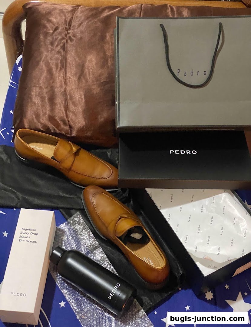 A pair of brown leather loafers from Pedro, presented with branded packaging and accessories.
