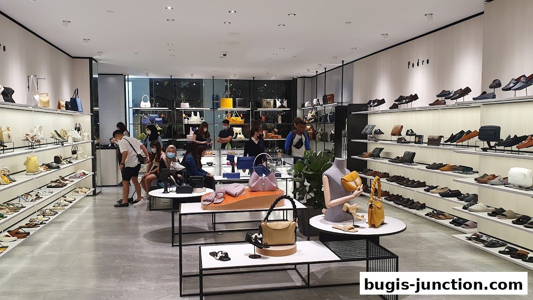 Interior view of a PEDRO shoe and handbag store with displays of merchandise and shoppers.