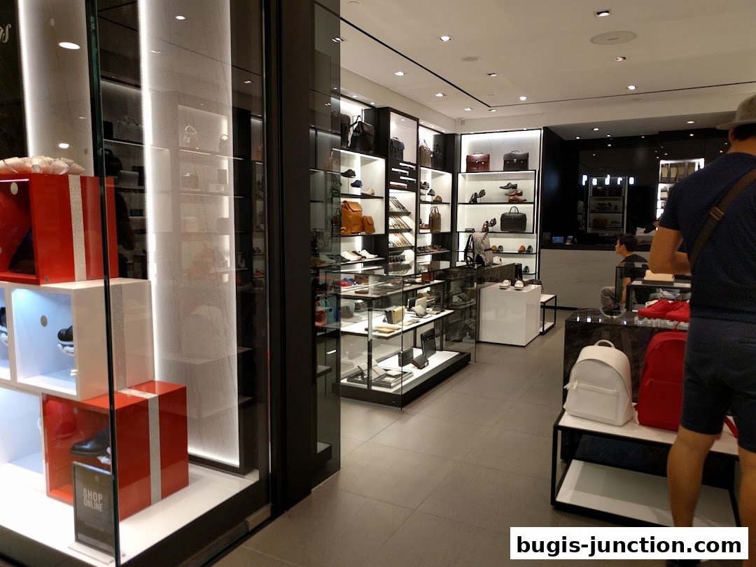 Interior view of a PEDRO shoe and bag store with displays of merchandise and customers.
