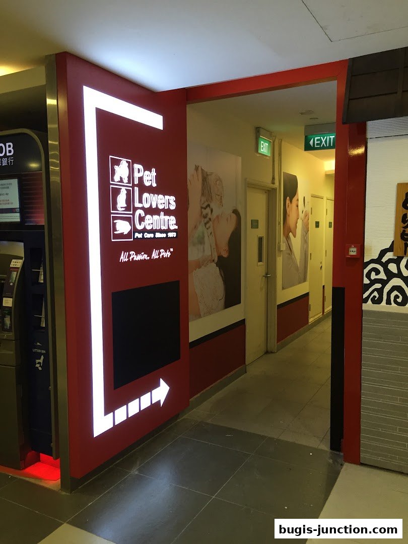 The entrance to Pet Lovers Centre, a pet care shop, with illuminated signage and posters.