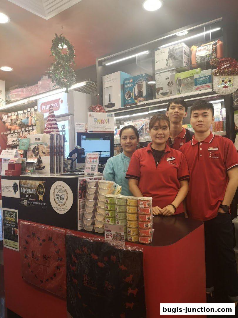 Staff members stand behind a counter at Pet Lovers Centre, surrounded by pet food and supplies.