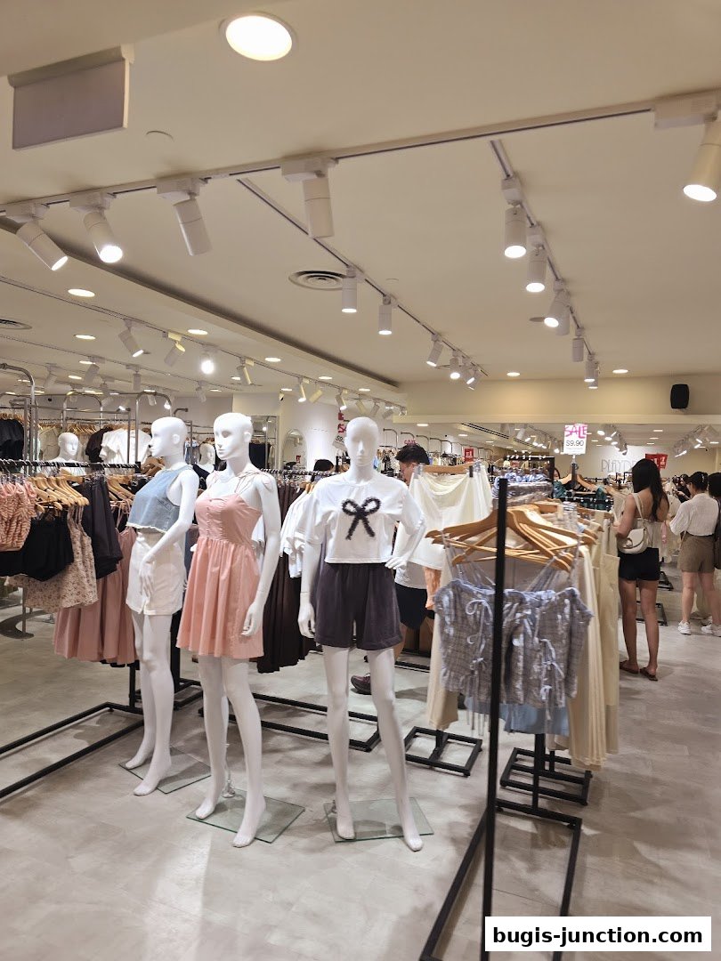 Mannequins display trendy outfits inside a well-lit clothing store.