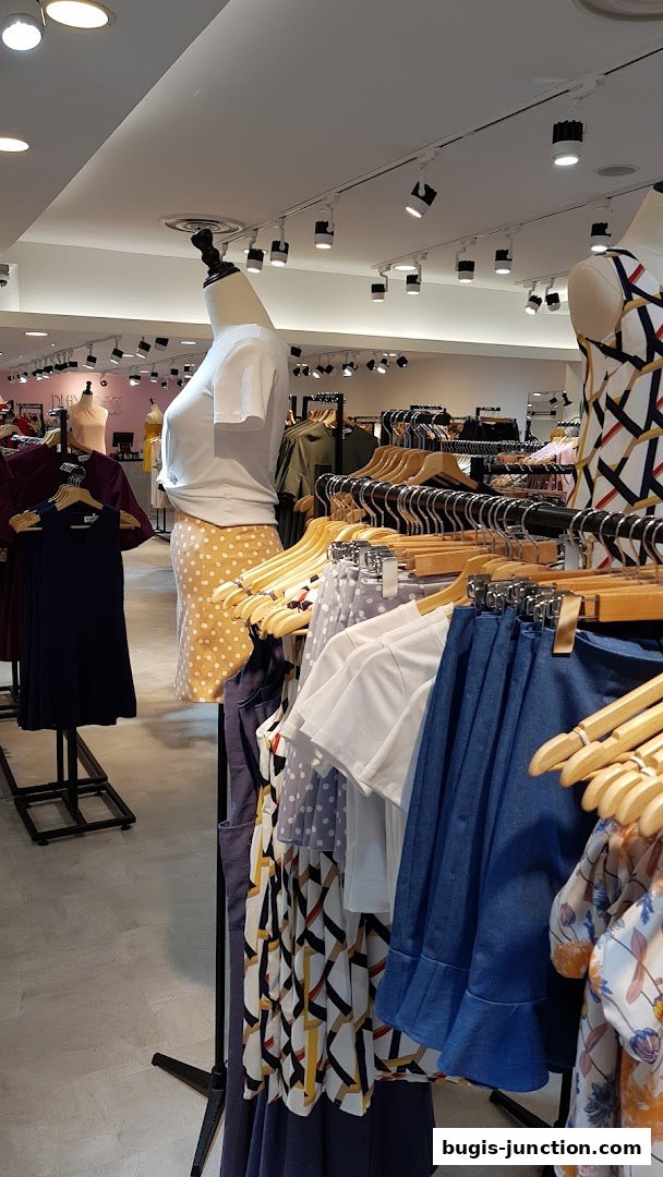 Mannequins and racks of stylish women's clothing displayed inside a boutique.