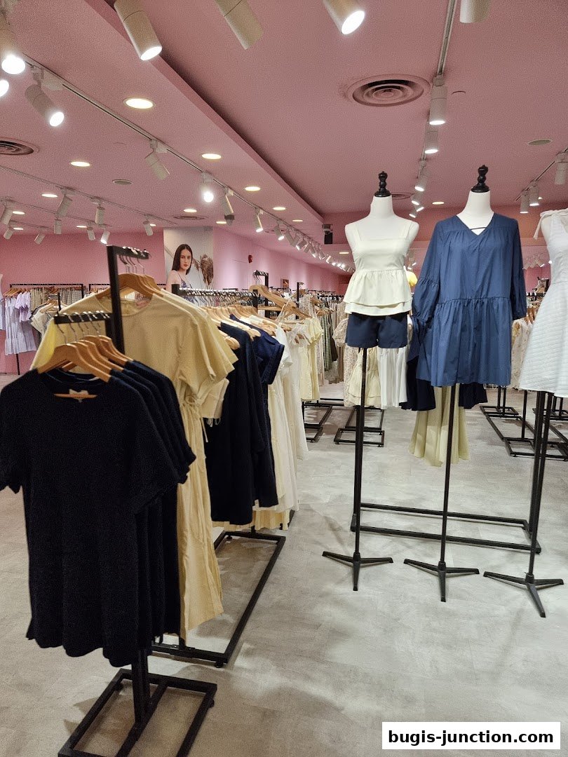 Interior view of a clothing store with racks of dresses and mannequins displaying outfits.