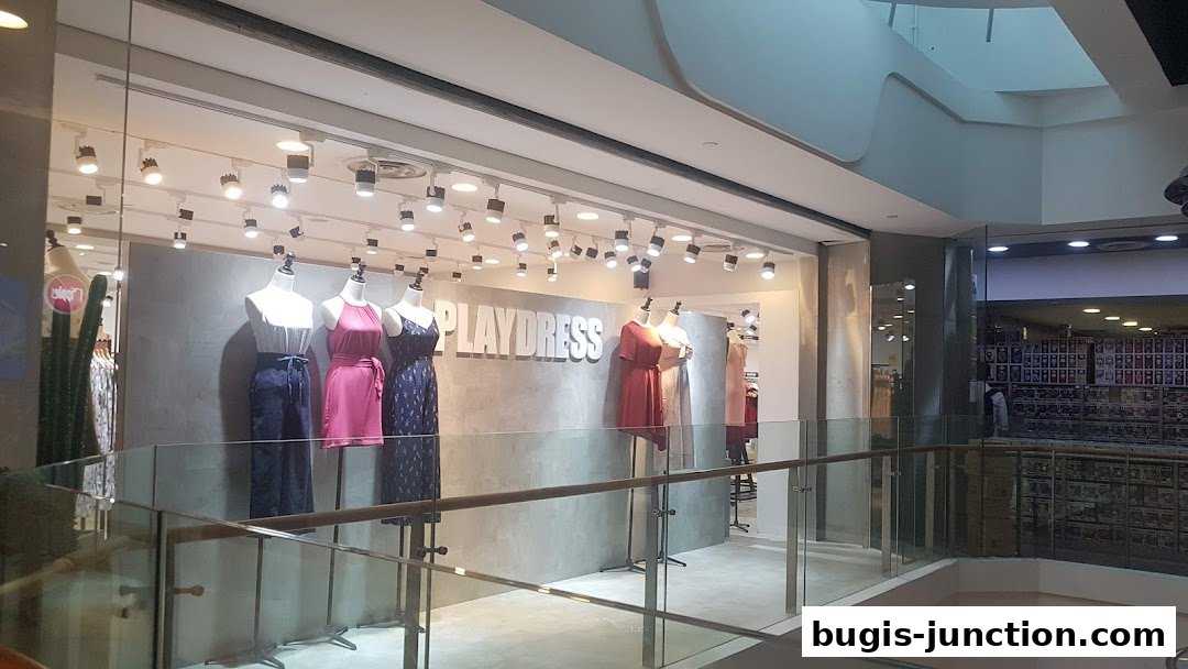 Playdress store interior with mannequins showcasing dresses and a modern, minimalist design.