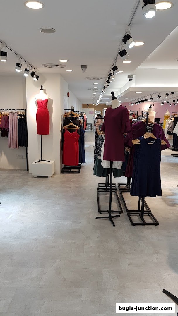 Interior view of a clothing store with mannequins displaying dresses and racks of apparel.