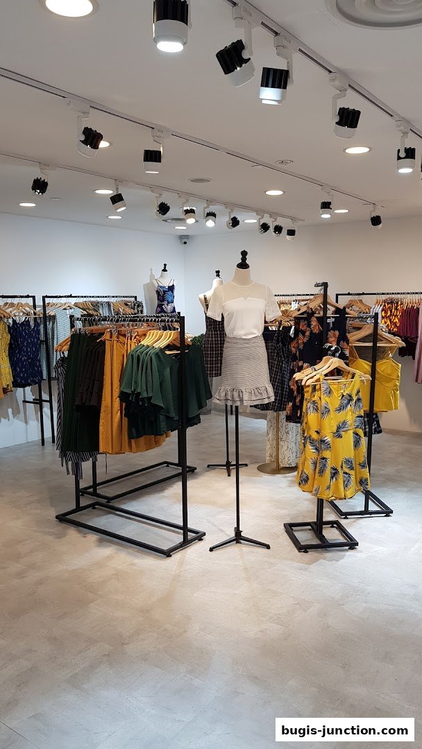Interior view of a clothing store with racks of dresses and mannequins displaying outfits.