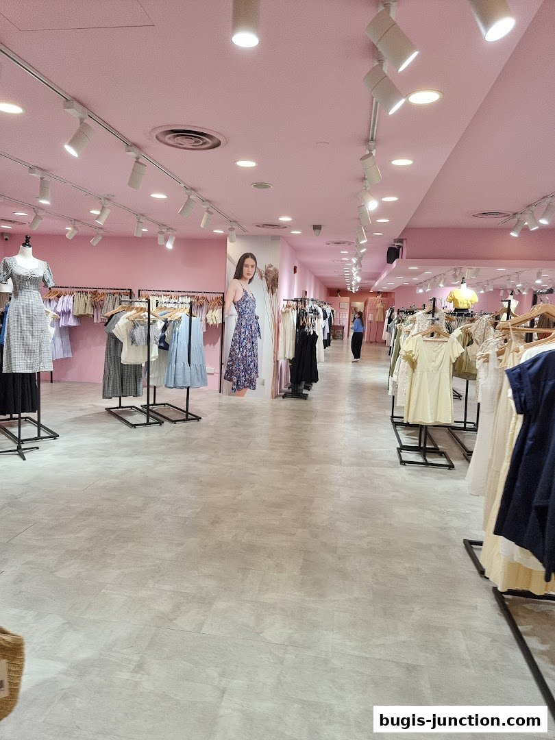 Interior view of a brightly lit clothing store with racks of dresses and apparel.