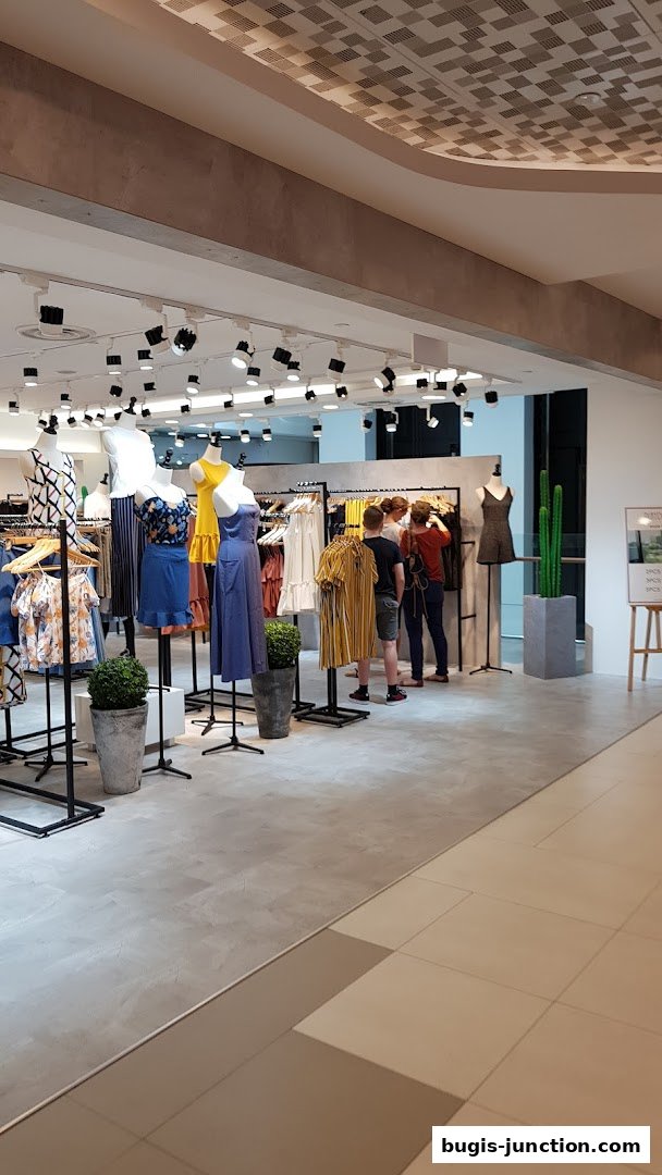 A well-lit clothing store interior with mannequins displaying dresses and racks of apparel.