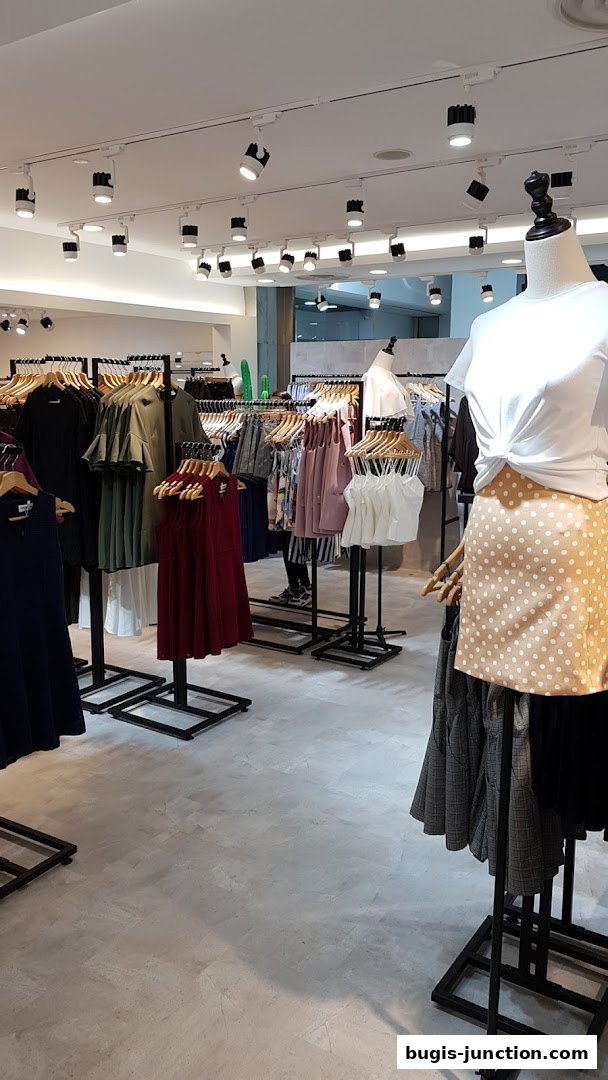 Interior view of a clothing store with racks of dresses, tops, and skirts on display.
