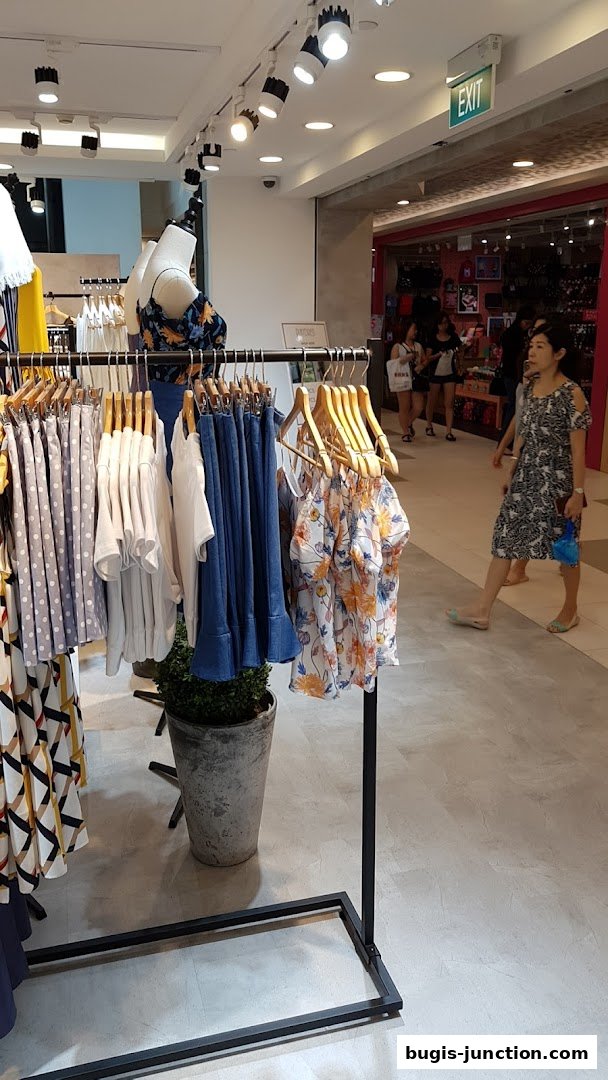 A clothing store interior with mannequins and racks of women's apparel.