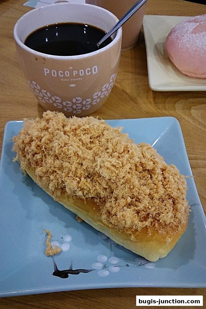 A fluffy bun topped with savory shredded meat, served with a cup of coffee.