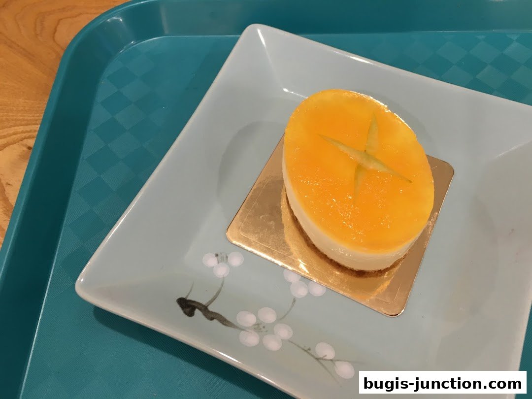 A close-up of a delicate oval-shaped dessert with a bright orange glaze and a star-shaped garnish.