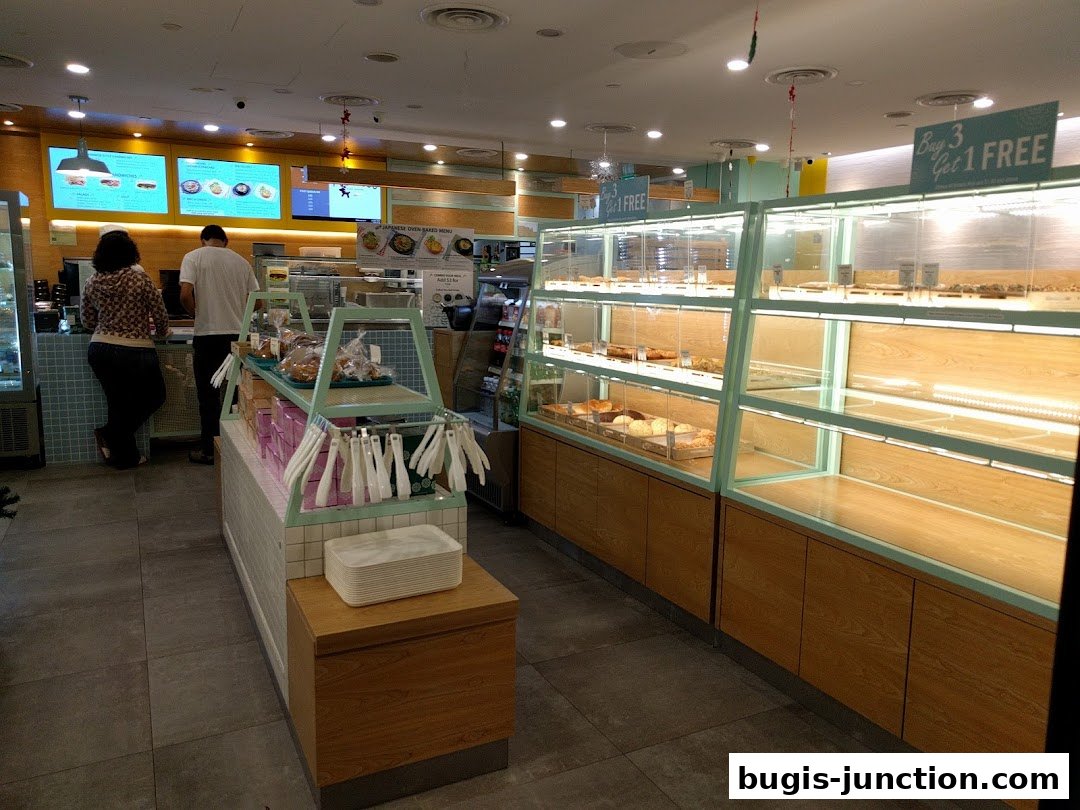 Interior view of a bakery with display cases filled with baked goods and customers ordering.