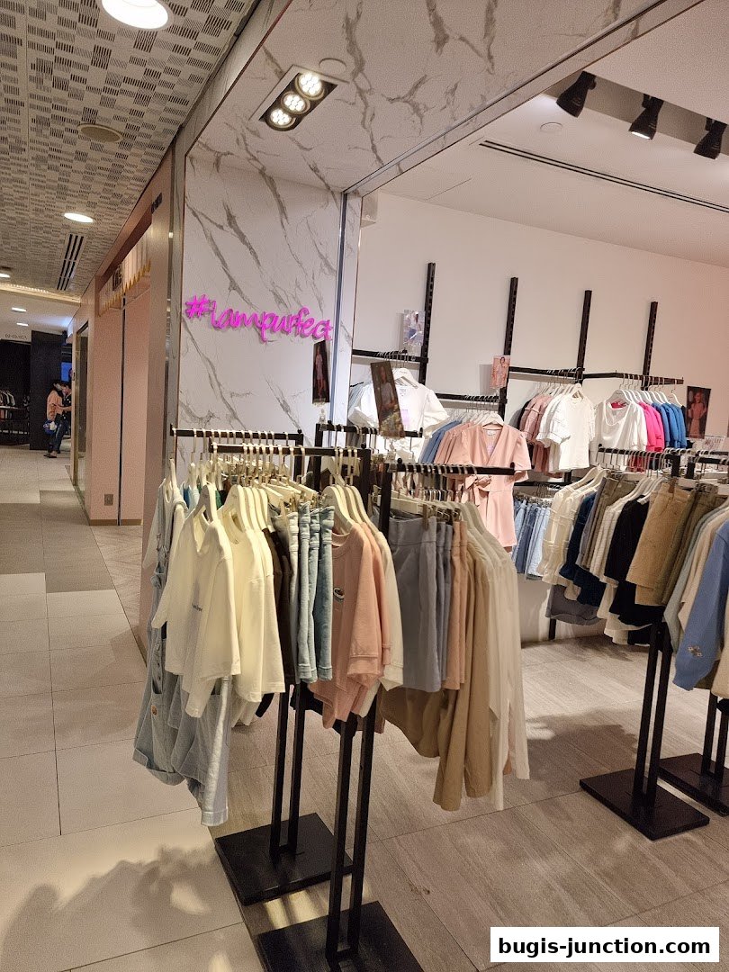 A clothing store interior with racks of stylish apparel, featuring a neon sign.