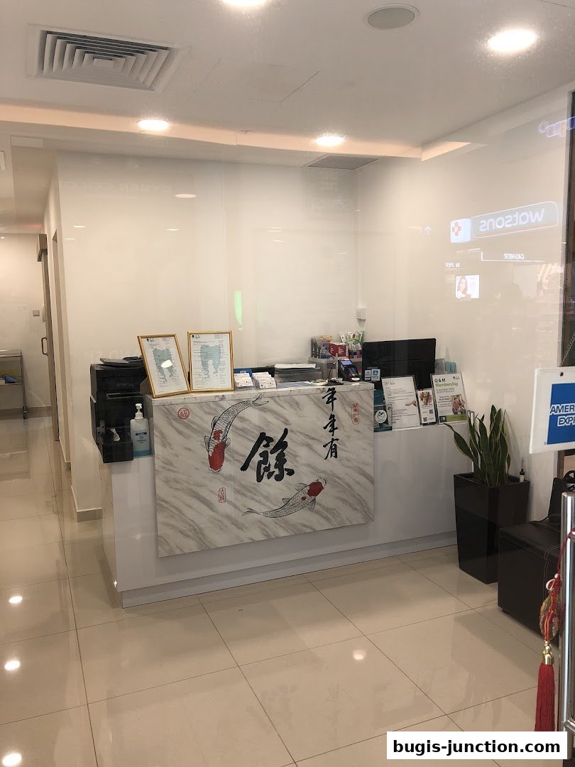 The reception counter of Q M Dental Centre Bugis Junction with koi fish art and dental certificates.
