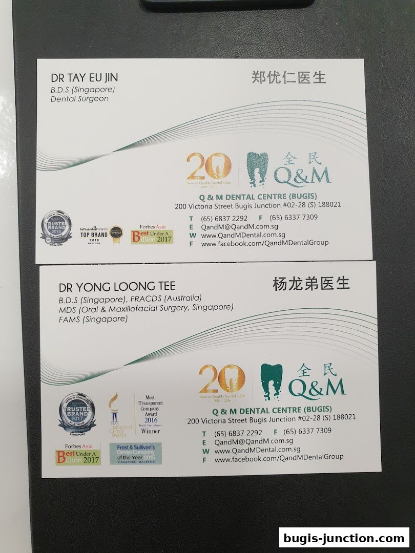 Business cards for Q & M Dental Centre featuring dentists and awards.