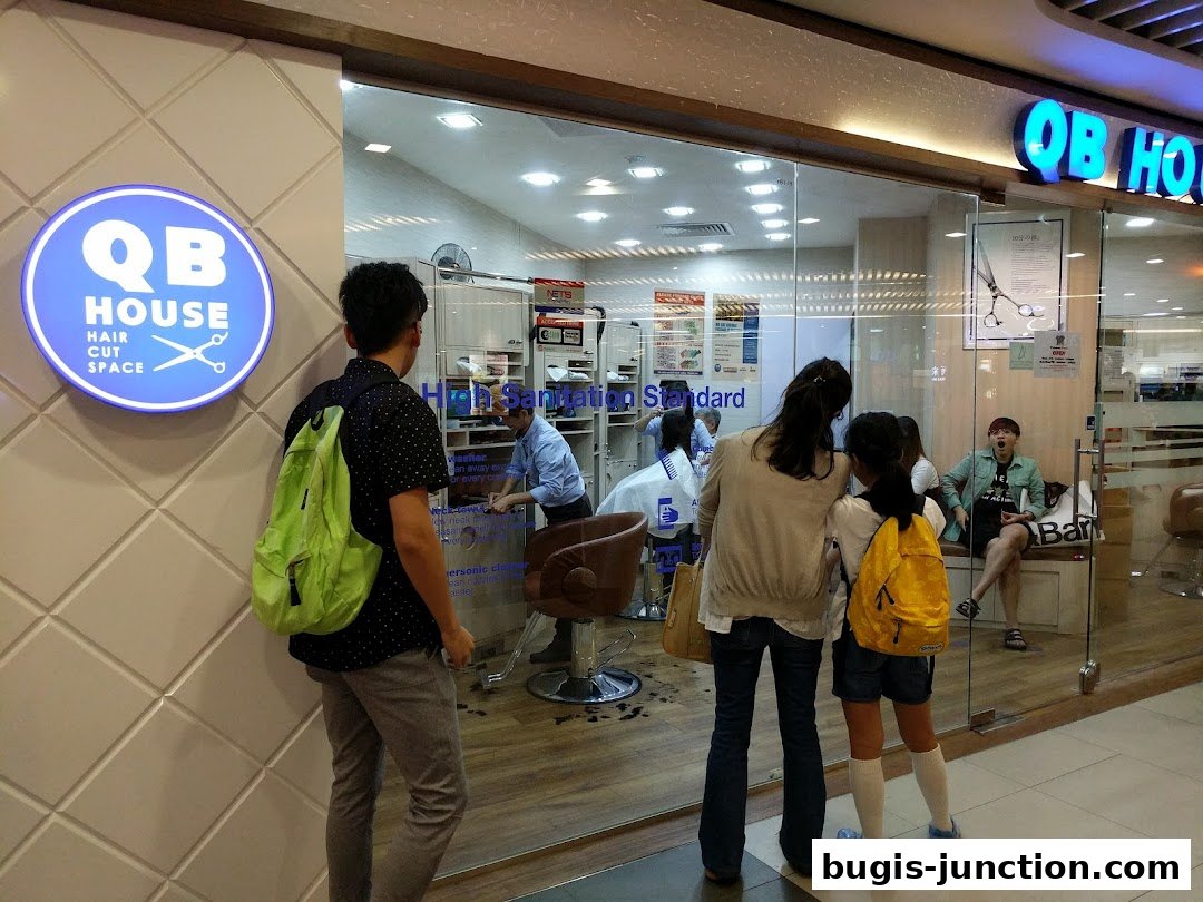People are looking into a hair salon with stylists working and customers waiting.