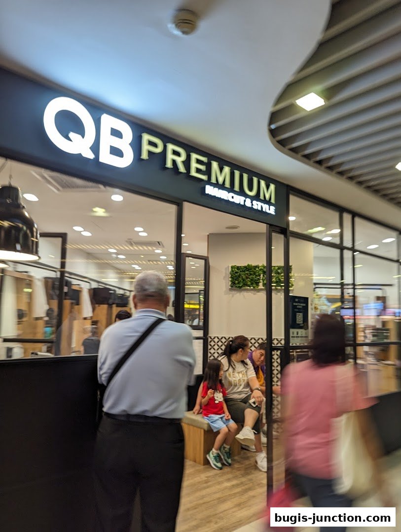 The entrance of QB PREMIUM, a haircut and style salon, with people waiting inside.