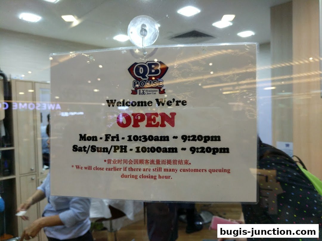 A sign on a glass door indicating the shop is open with operating hours.