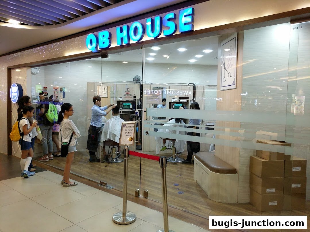 People queue outside QB House, a hair salon, where a stylist is cutting a customer's hair.