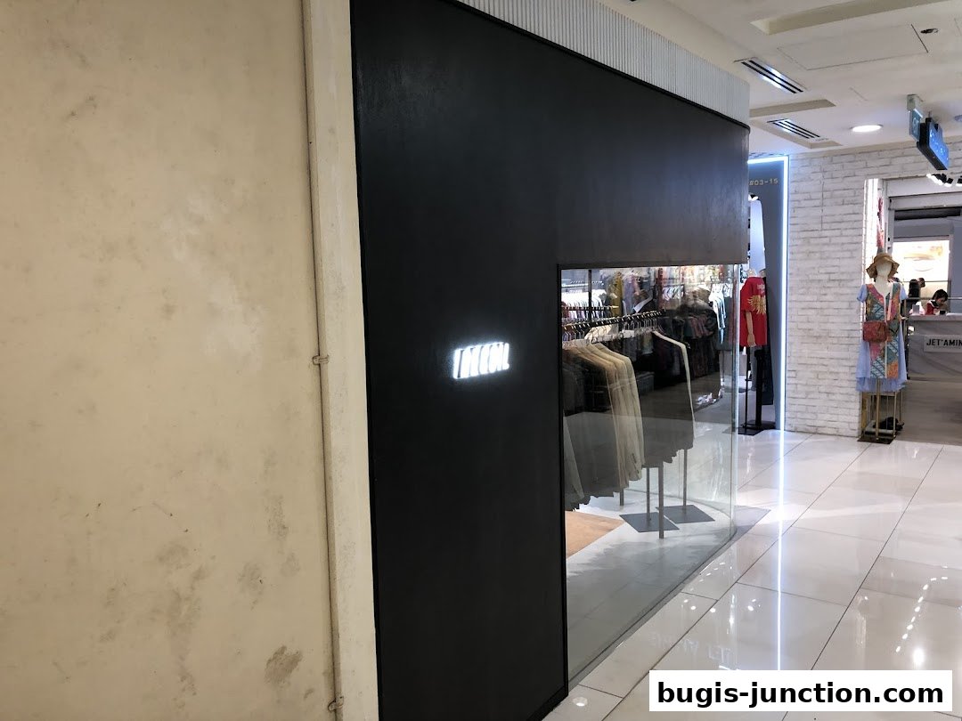 The modern storefront of RECOIL, featuring a black facade and a glass display showcasing clothing.
