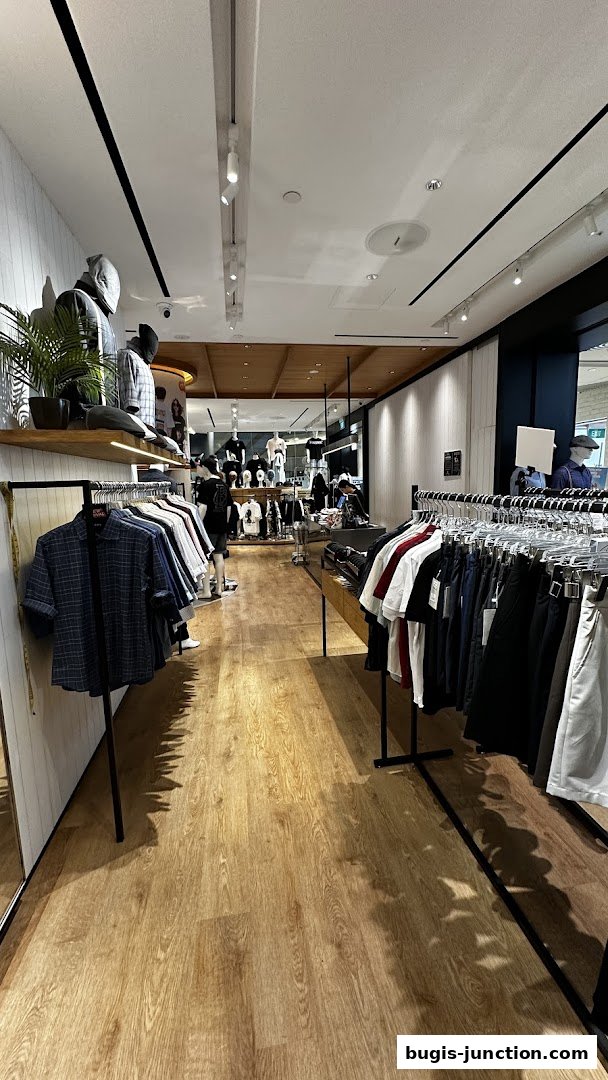 Interior view of a modern clothing store with racks of apparel and mannequins.