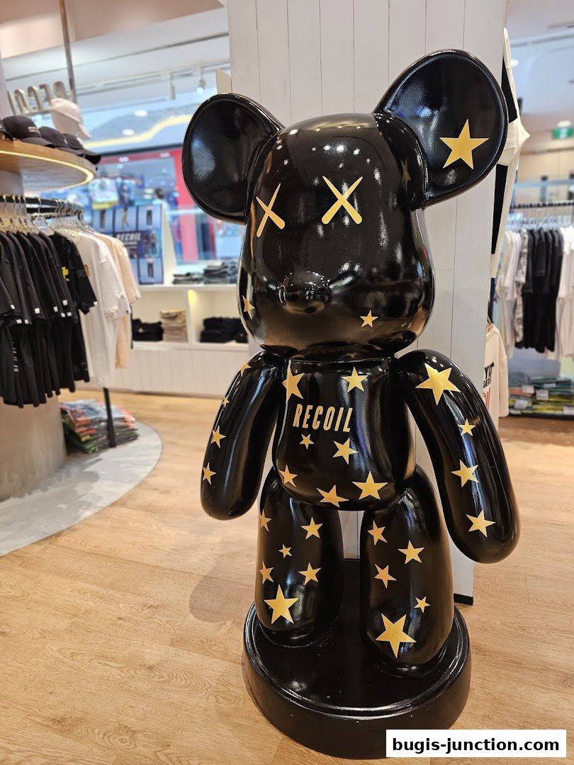 A large black bear statue with gold stars and the word RECOIL inside a clothing store.