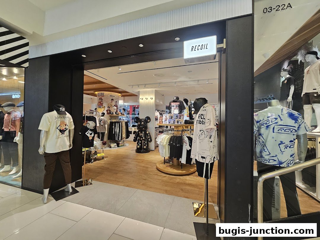 The entrance of RECOIL, a clothing store, showcasing mannequins with graphic tees and apparel.