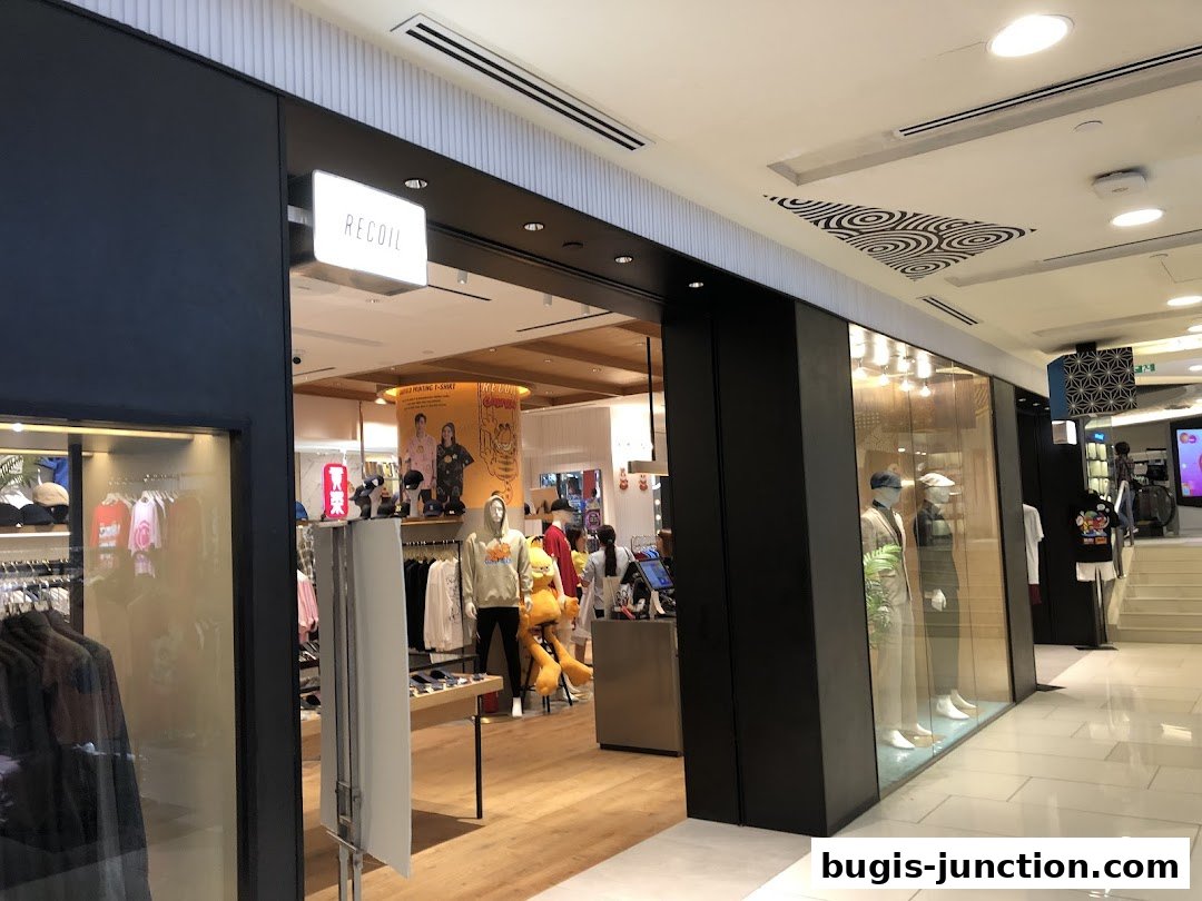 The entrance of RECOIL, a clothing store, showcasing mannequins and apparel inside.