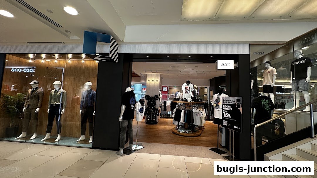 The entrance and display windows of the RECOIL fashion store, showcasing mannequins and apparel.