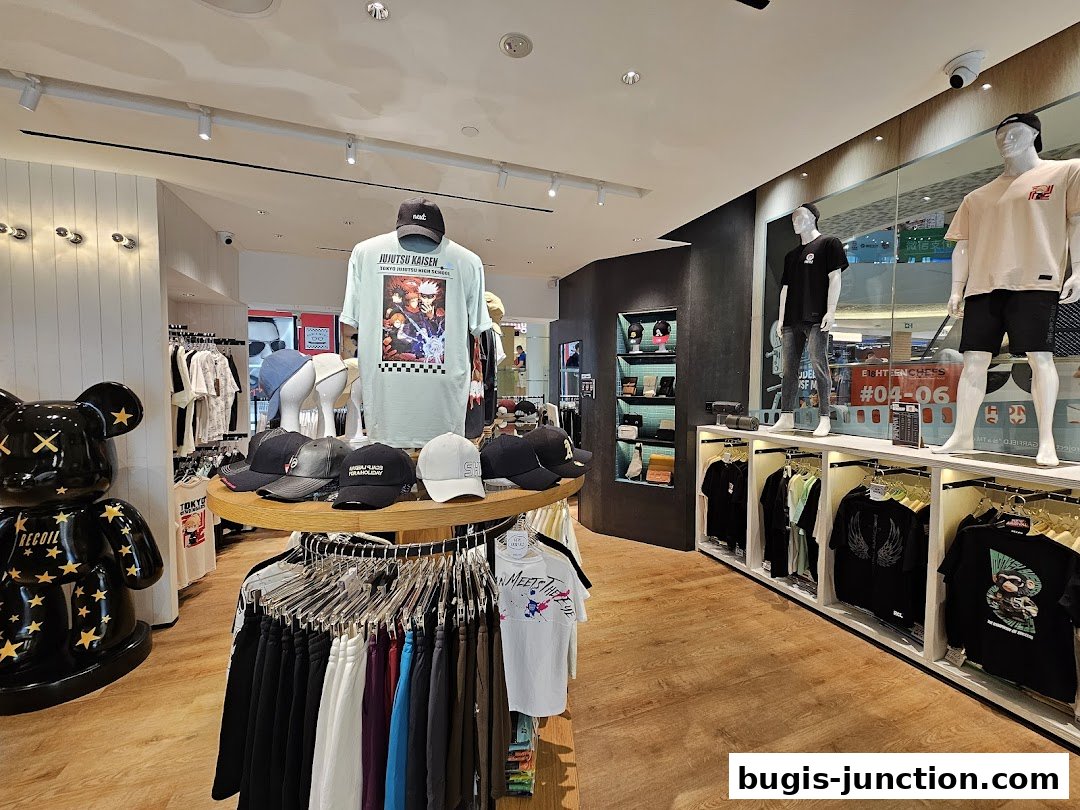 Interior view of a clothing store displaying t-shirts, caps, and a large decorative bear.