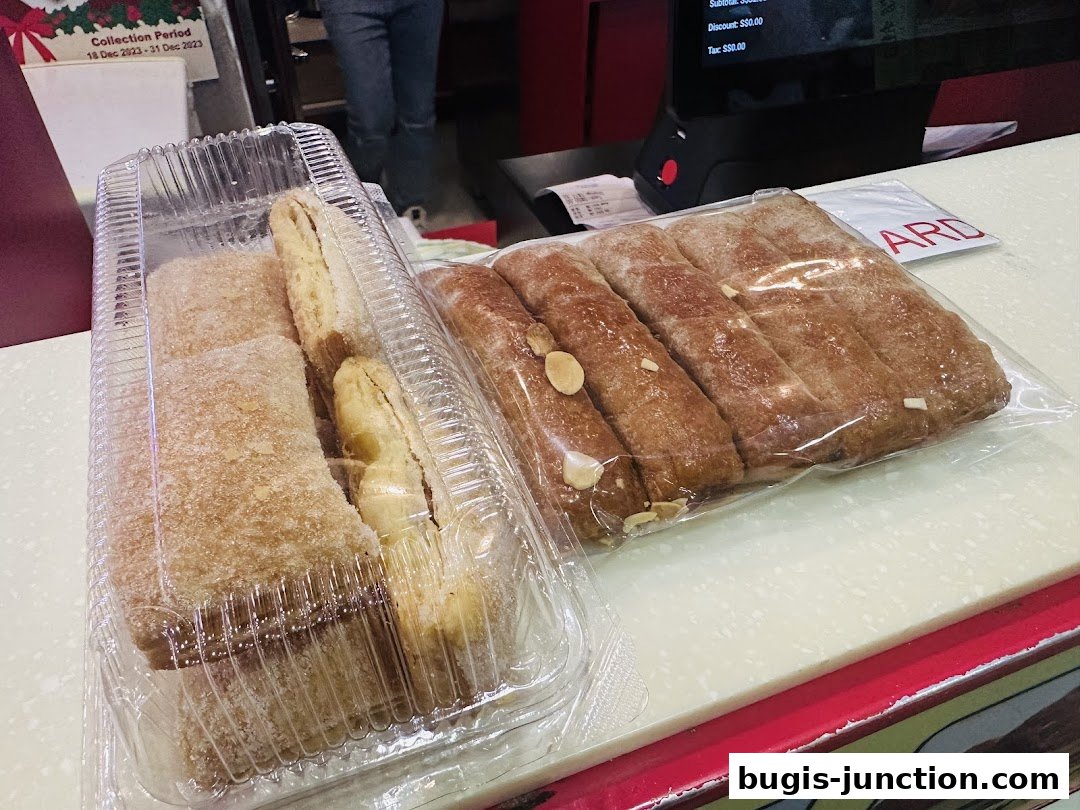 Two containers of freshly baked apple strudels, one dusted with sugar, the other topped with almonds.