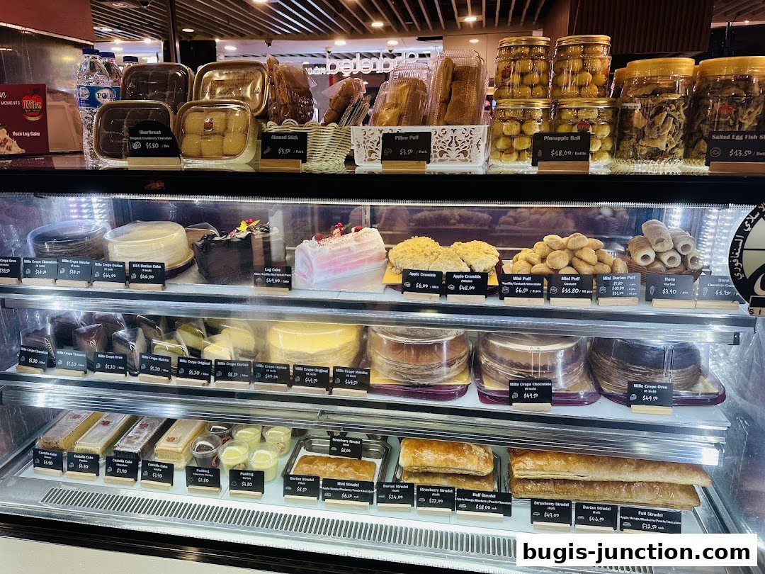 A display case filled with various cakes, pastries, and jars of snacks from Ritz Apple Strudel.