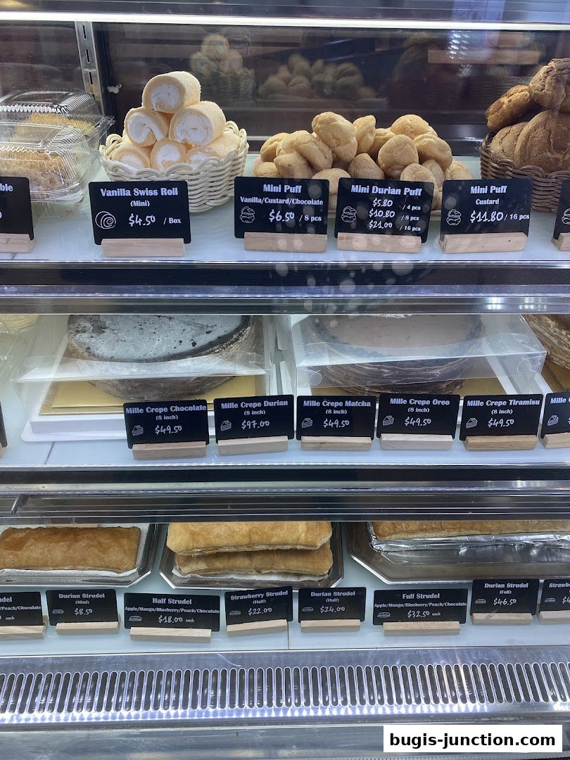 A display case filled with various pastries including strudels, mille crepes, and mini puffs.