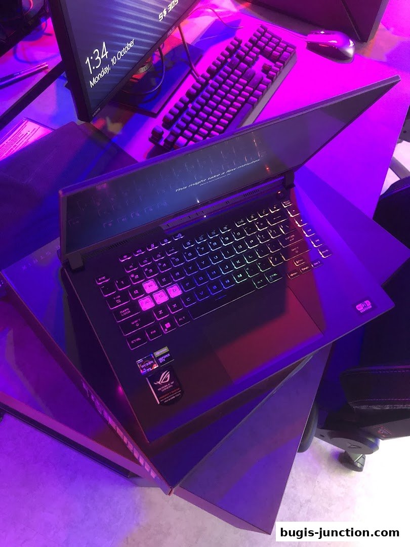 A gaming laptop with RGB keyboard and a monitor displaying the date and time.