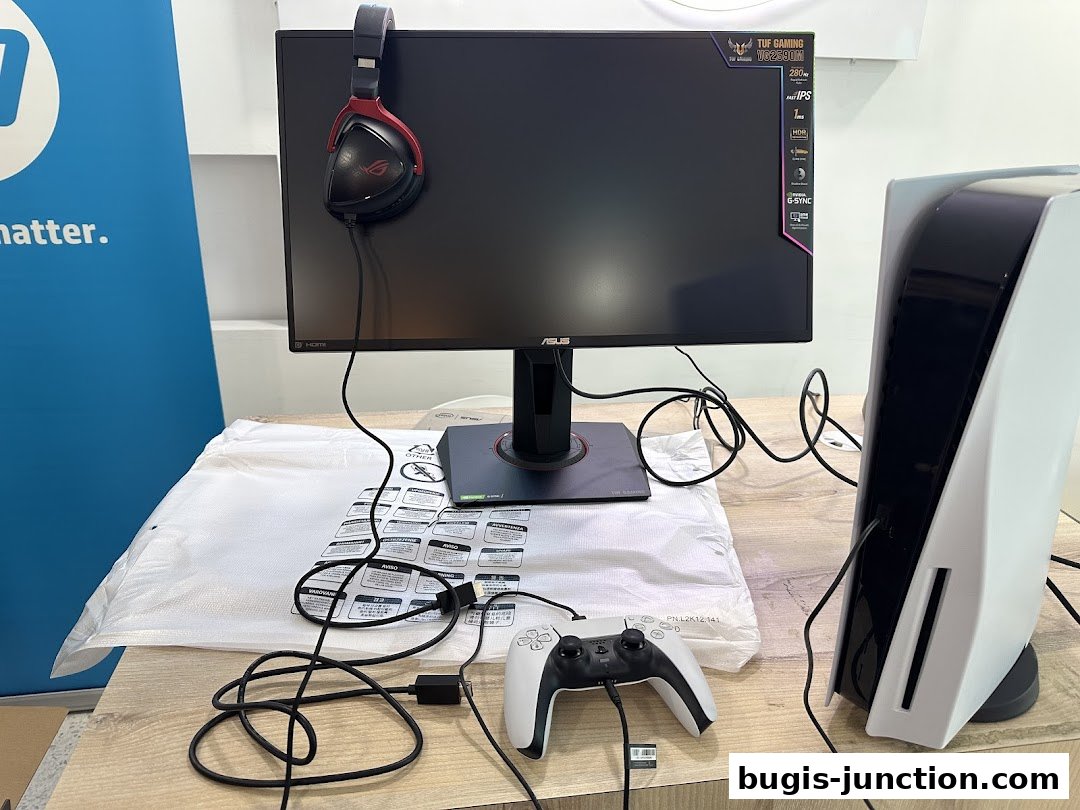 A gaming setup featuring a monitor, headphones, PlayStation 5, and controller.