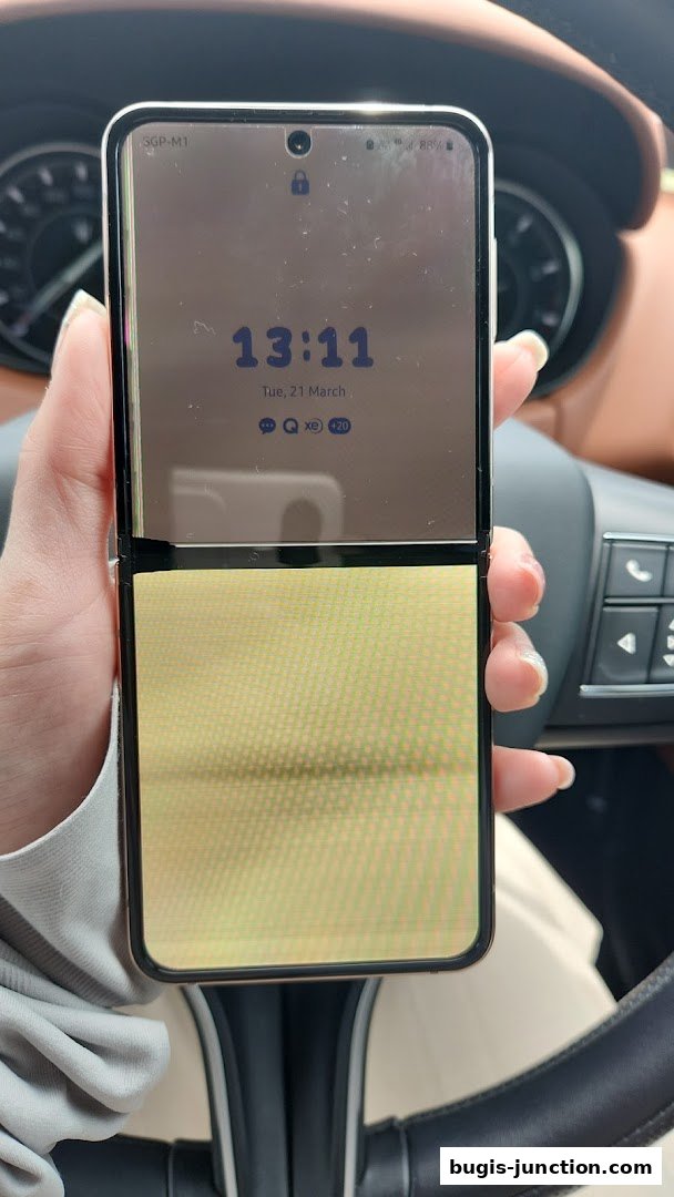 A person holds a Samsung foldable phone displaying the time and date on its screen.