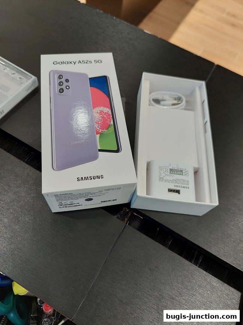 A Samsung Galaxy A52s 5G phone and its charger are displayed in their packaging.