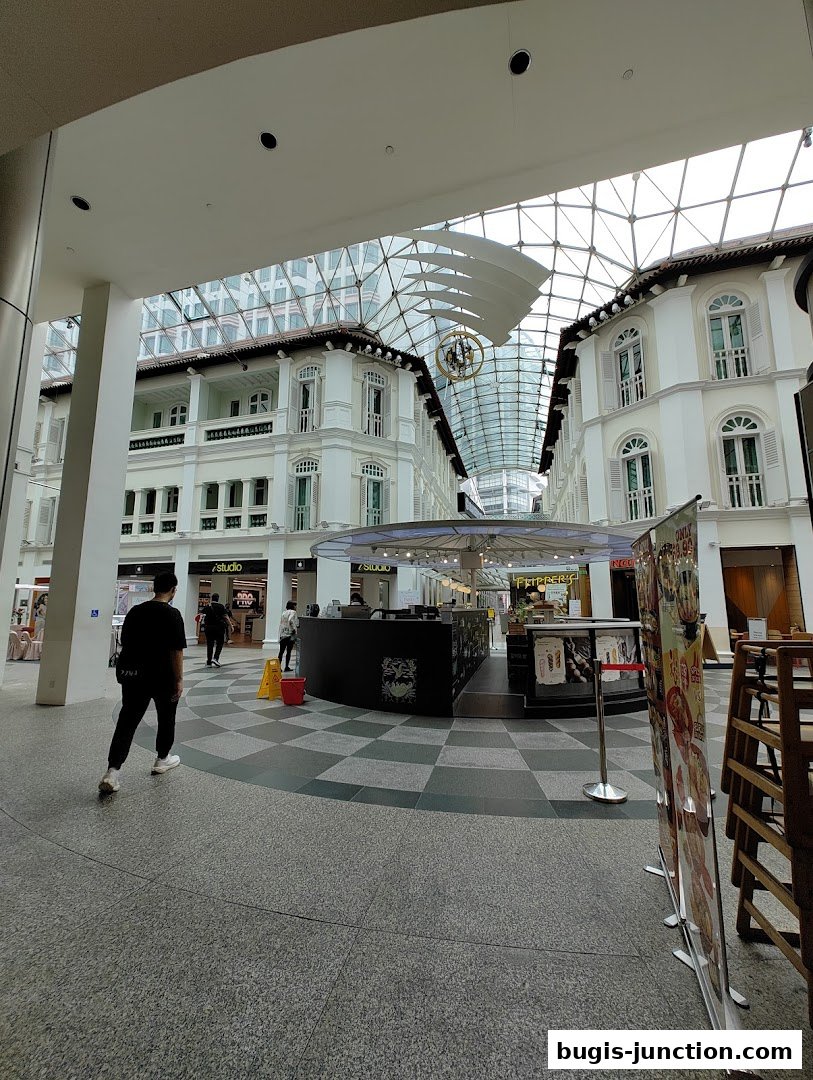 A view of the Bugis Junction shopping mall interior with shops and people walking.
