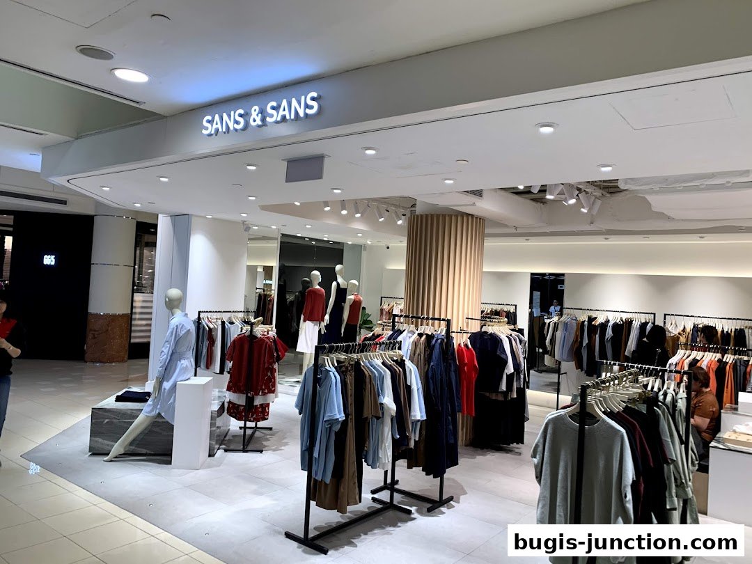 The entrance of a modern clothing store with mannequins and racks of apparel.