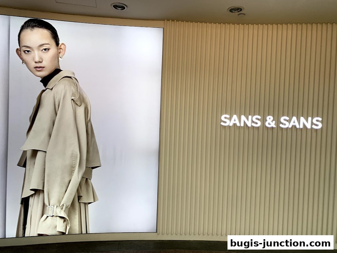 A fashion display featuring a model in a trench coat and the shop's name.