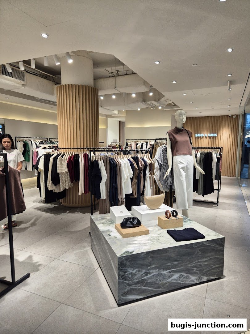 Interior view of a clothing store with racks of apparel and a display table.