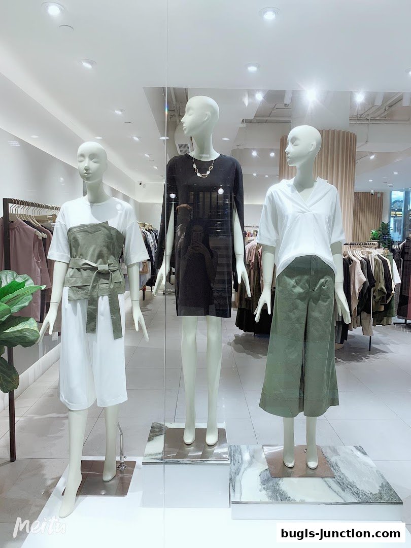 Mannequins in a shop window display showcasing stylish women's clothing.