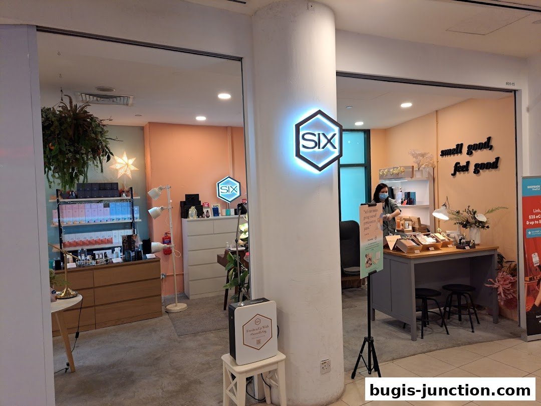 The entrance of a Scent by SIX shop with products displayed and a staff member.