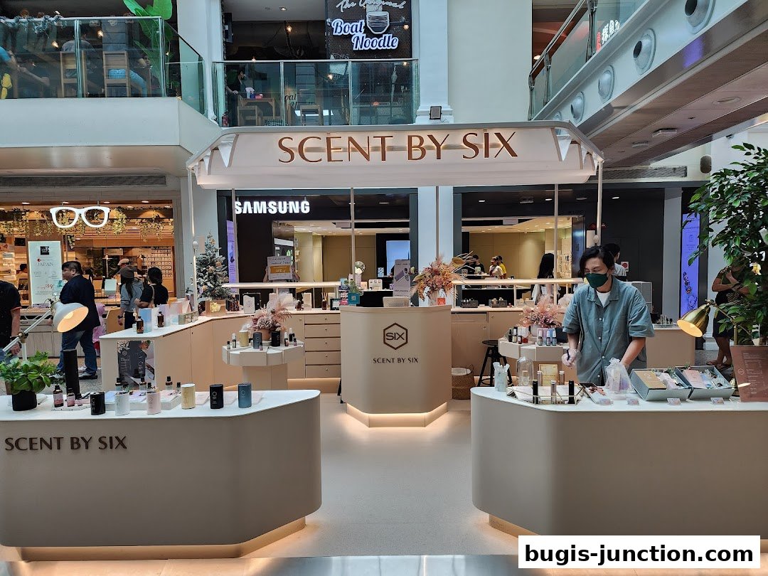 A Scent by SIX store display with various perfume bottles and a staff member.